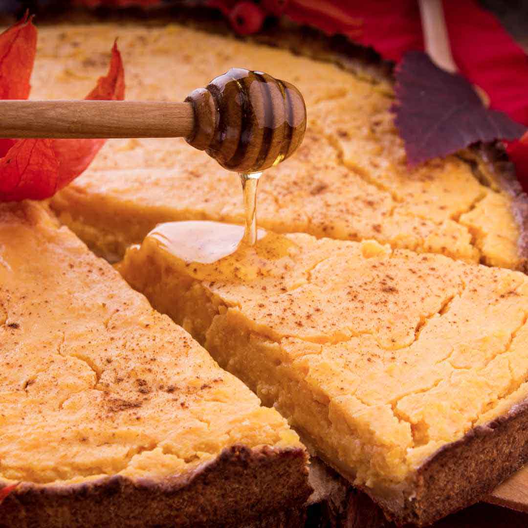 "Golden-brown homemade pumpkin pie sweetened with honey" "A delicious slice of honey-infused pumpkin pie on a plate" "Freshly baked traditional pumpkin pie with a golden crust"