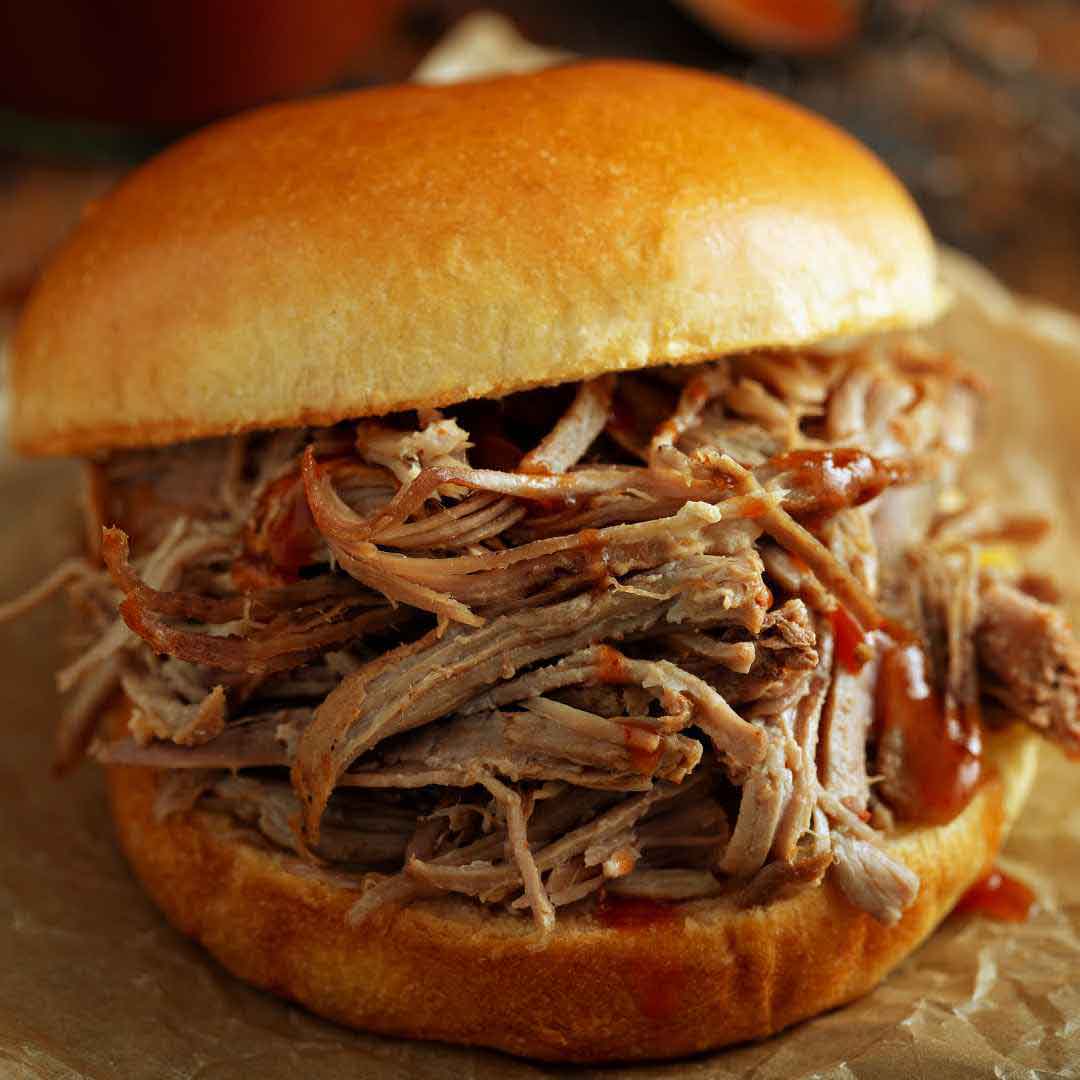 Smoked pulled pork sandwich topped with homemade honey BBQ sauce Close-up of pulled pork dripping with sweet and spicy honey barbecue sauce Honey-glazed pulled pork sandwich served on a fresh roll Delicious smoked pork sandwich with honey-infused BBQ sauce Homemade honey BBQ pulled pork sandwich ready to eat